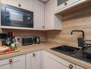 Una cocina moderna con armarios blancos, un microondas negro, un tostador y un lavamanos.