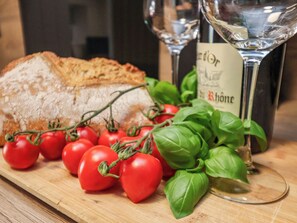 Ein Holzschnittbrett mit Brot, Tomaten, Basilikum und zwei Weingläsern.