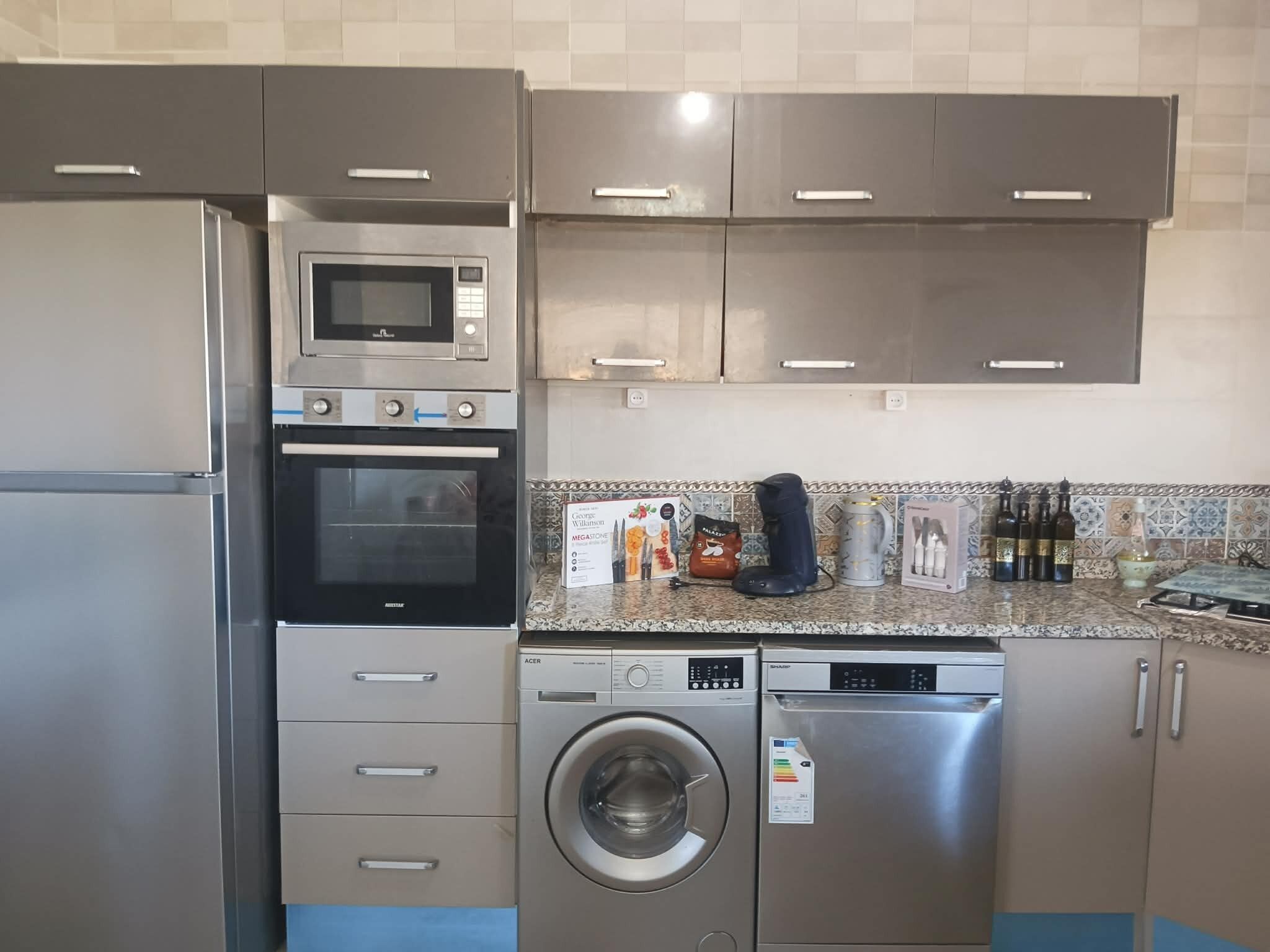 A kitchen with stainless steel appliances, including a microwave, oven, and dishwasher, with a tiled backsplash and cabinets.