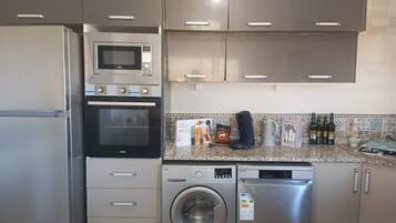 A kitchen with stainless steel appliances, including a microwave, oven, and dishwasher, with a tiled backsplash and cabinets.
