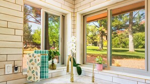 Une salle de bain dotée d’un grand lavabo, de deux robinets dorés et offrant une vue sur un terrain de golf grâce à de grandes fenêtres.