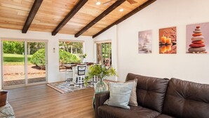 Un vaste salon doté d’un plafond en bois, d’un canapé en cuir marron et d’un coin repas avec une table et des chaises.