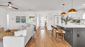 A modern kitchen with white cabinets, a central island, and pendant lighting. - Palms of the Isles (St. Petersburg)