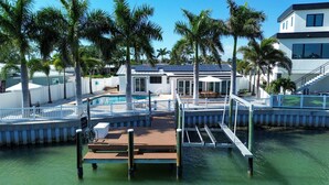 A pool area with a wooden deck, palm trees, and a building with a white facade. - Palms of the Isles (St. Petersburg)