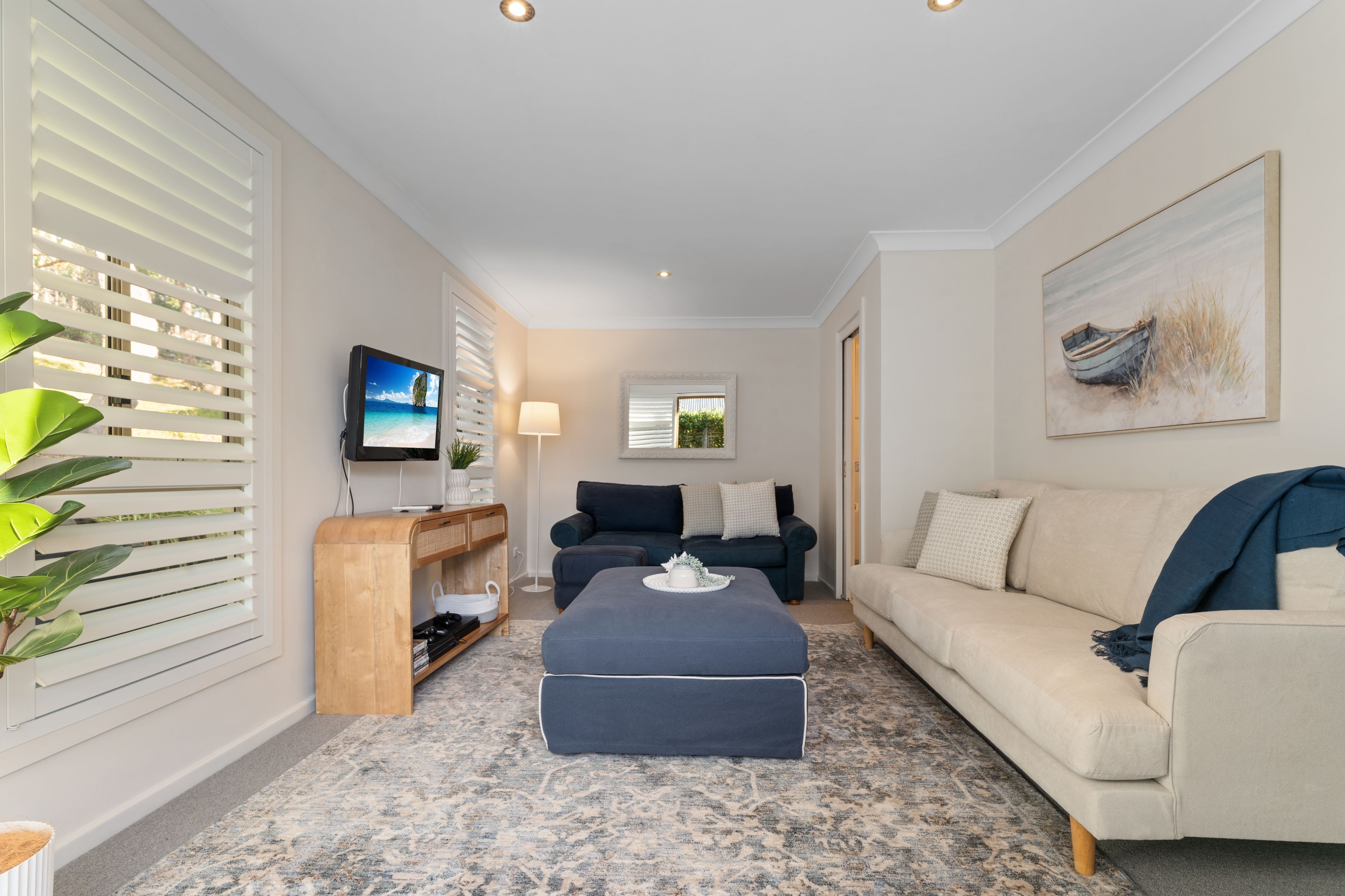 A modern living room with a flat-screen TV, a sofa, a coffee table, and a painting on the wall.