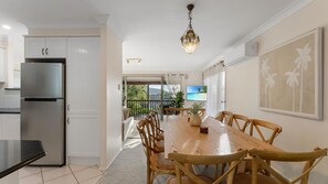 A modern kitchen with a stainless steel refrigerator, wooden dining table with chairs, and a view of the outdoors. - Flannel Flower Beach House (Shoal Bay)