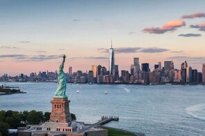 The Statue of Liberty with a city skyline in the background. - Modern Home Near MetLife | 2BR | Free Parking (Jersey City)