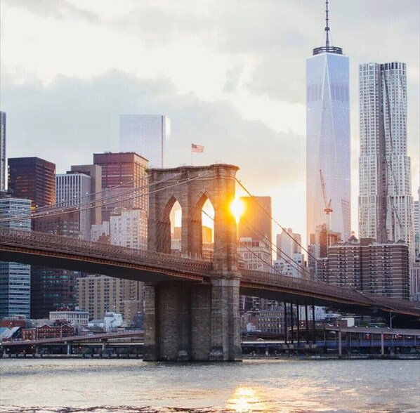 A bridge with stone arches and a city skyline in the background. - Modern Home Near MetLife | 2BR | Free Parking (Jersey City)