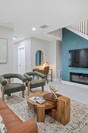 A stylish sitting area with comfortable chairs, a large Smart TV, and a fireplace for relaxed evenings at home. - Three Little Birds | Historic Luxury Retreat (Lakeland)
