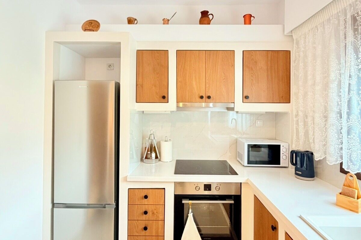 Eine moderne Küche mit Einbaukühlschrank, Mikrowelle, Herd und Backofen. Über der Arbeitsfläche hängt eine Leuchte.