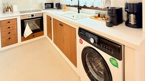 A modern kitchen with wooden cabinets, a built-in oven, a dishwasher, and a coffee maker. - Kapetánissa Concept Studios (Stalida)
