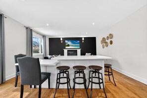 Una cocina moderna con una isla blanca, taburetes de bar y una silla de comedor.