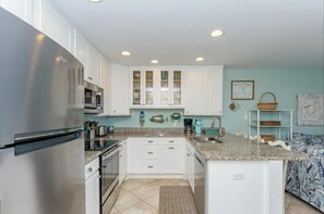 A kitchen with white cabinets, a stainless steel refrigerator, and a granite countertop.