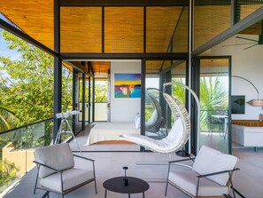 A modern interior with a glass balustrade, a hanging chair, and a dining area. - Stealing Time Costa Rica (Esterillos Oeste)