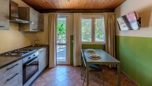 Une cuisine équipée d’une cuisinière à gaz, d’un four et d’un coin repas avec une table et des chaises.