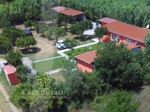 An aerial view of a residential area with red-roofed houses, green lawns, and a satellite dish on one of the roofs. - L'Agrumeto domos - Four Bedroom Apartment, Sleeps 8 (Teulada)