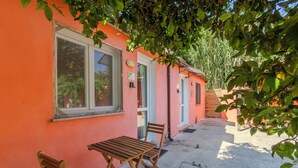 Un bâtiment à la façade rose, avec une fenêtre et une table entourée de deux chaises.