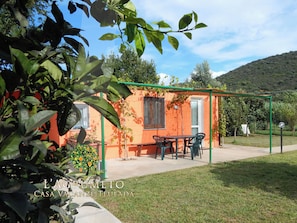 Une petite maison orange avec une terrasse, une table et des chaises.