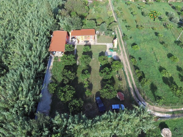 An aerial view of a property with a house, fenced garden, and parked cars.