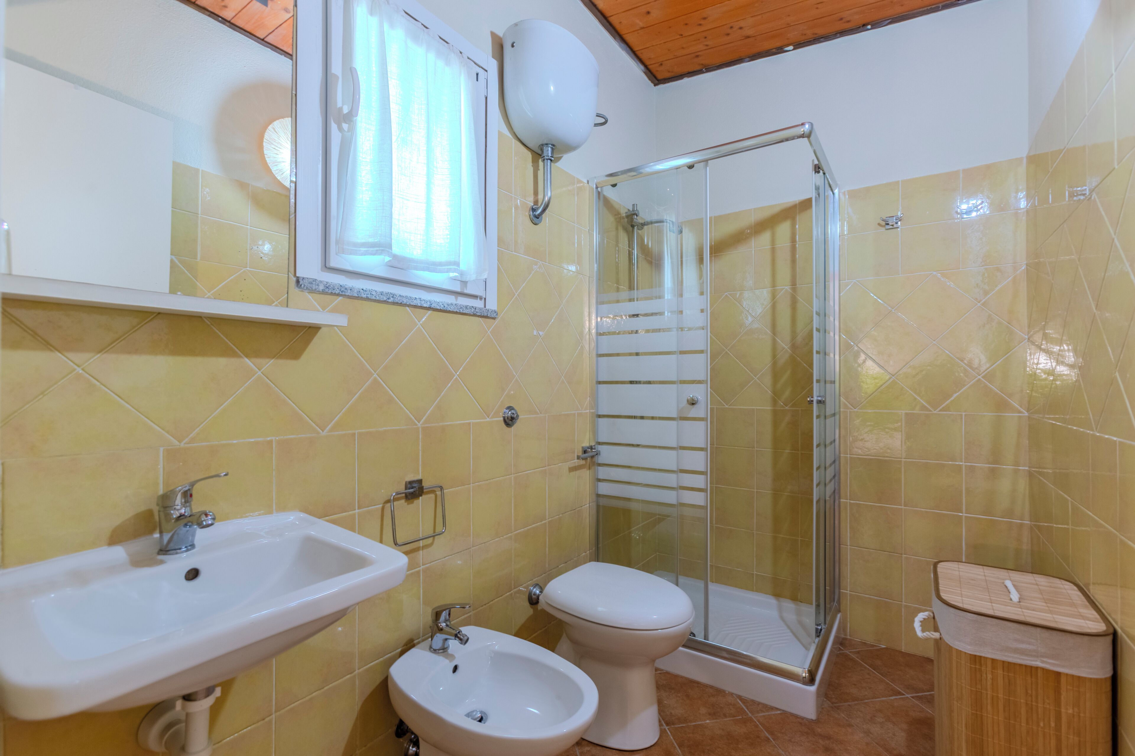 A bathroom with a sink, bidet, toilet, and glass-enclosed shower.