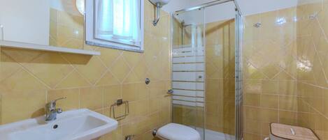 A bathroom with a sink, bidet, toilet, and glass-enclosed shower.