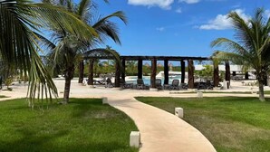 Ein Resort mit Poolbereich, Palmen und einem überdachten Gang.