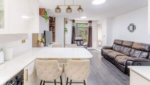Een moderne keuken met een eethoek, een leren bank en een kroonluchter.
