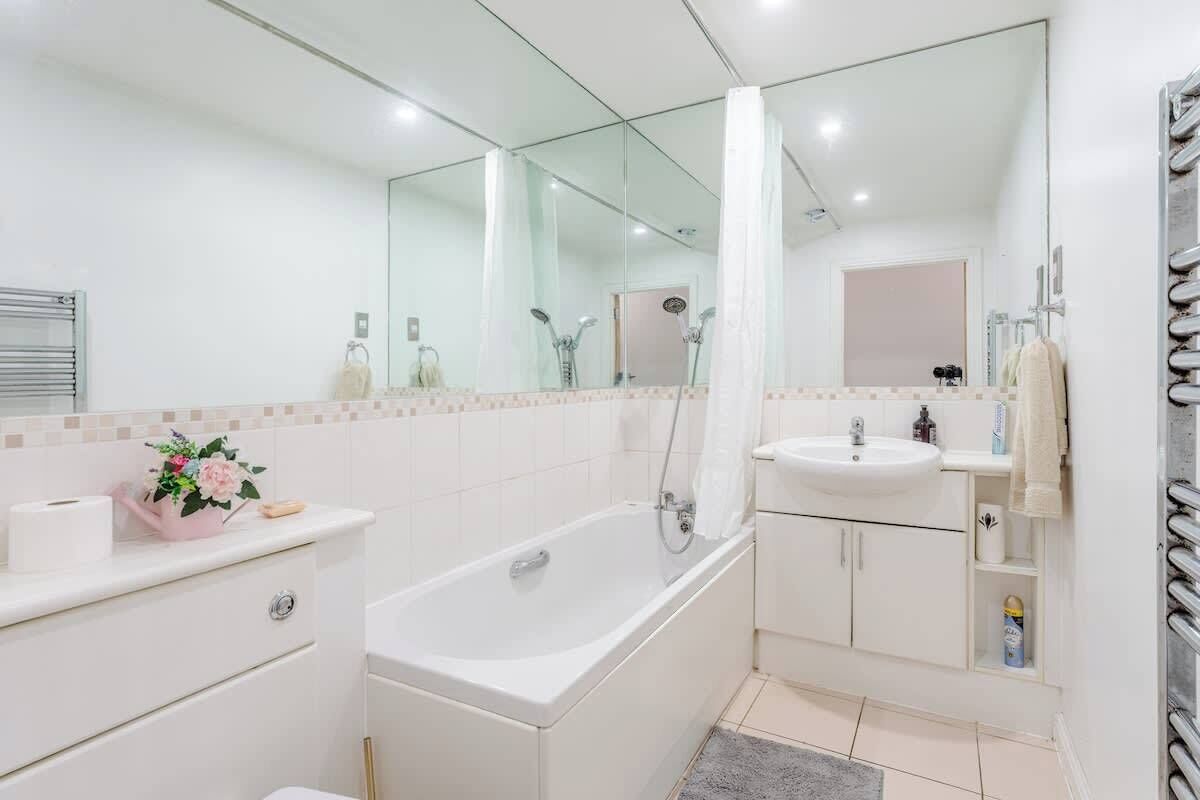 Un baño moderno con bañera, lavamanos, espejo y ducha.