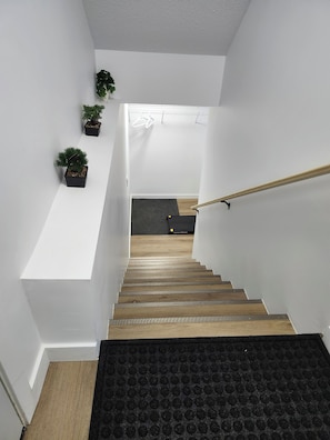 Eine Treppe mit Holzstufen, weißen Wänden und Blumentöpfen.