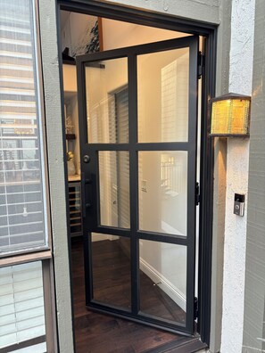 Eine moderne Eingangstür mit Fensterteil, Klingel und Wandleuchte.