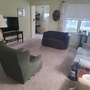 Una sala de estar con televisor, sofá, sillón y ventana con vista.
