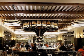 Ein Restaurant mit Barbereich, Holzbalkendecke und hängenden, runden Kronleuchtern.