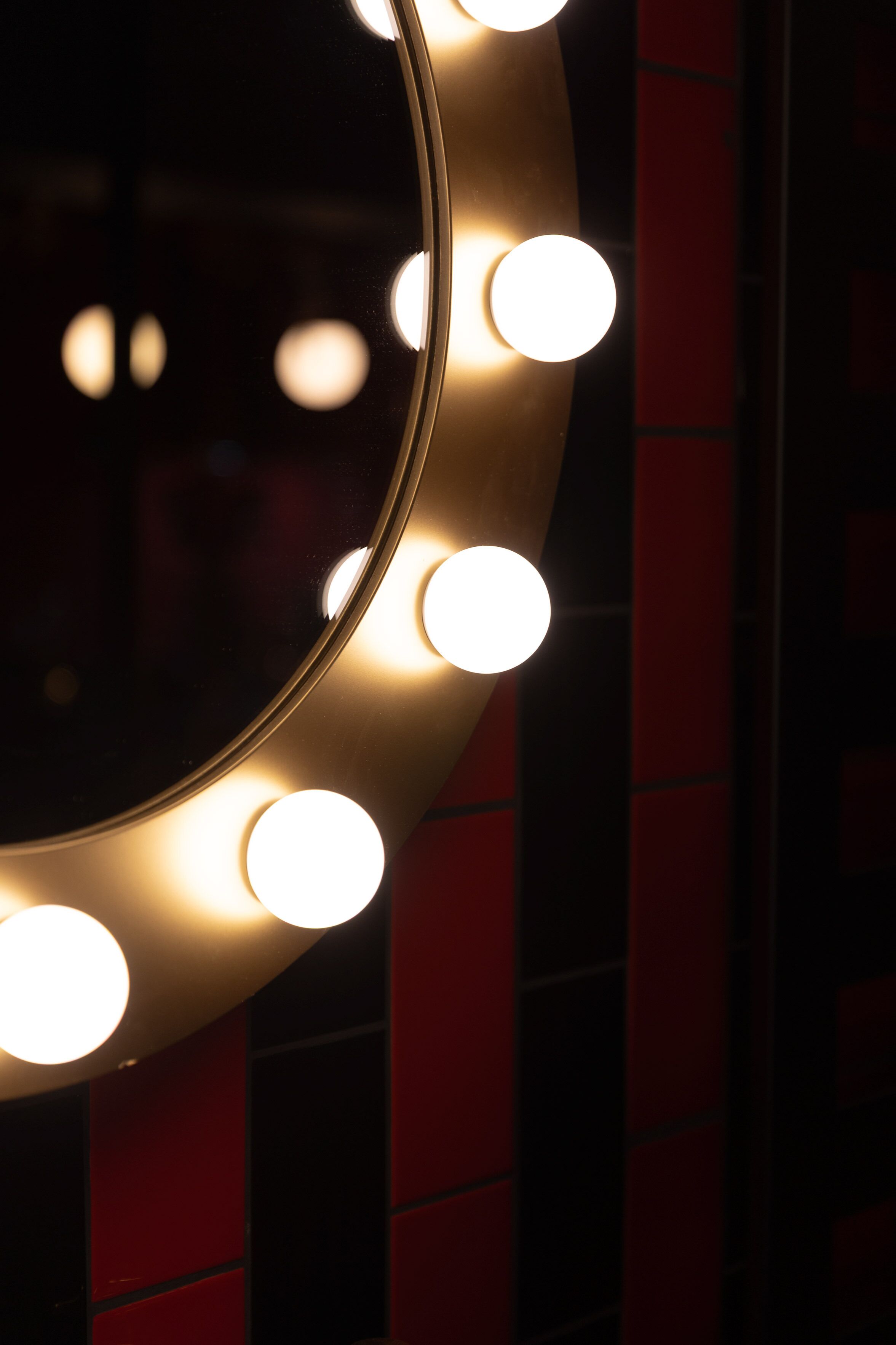 A circular mirror with lights around its edge.
