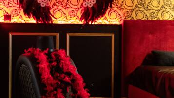 A room with a patterned wallpaper, a black upholstered headboard, and a red accent wall.