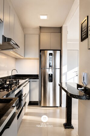 A modern kitchen with stainless steel appliances, a marble countertop, and a built-in oven.