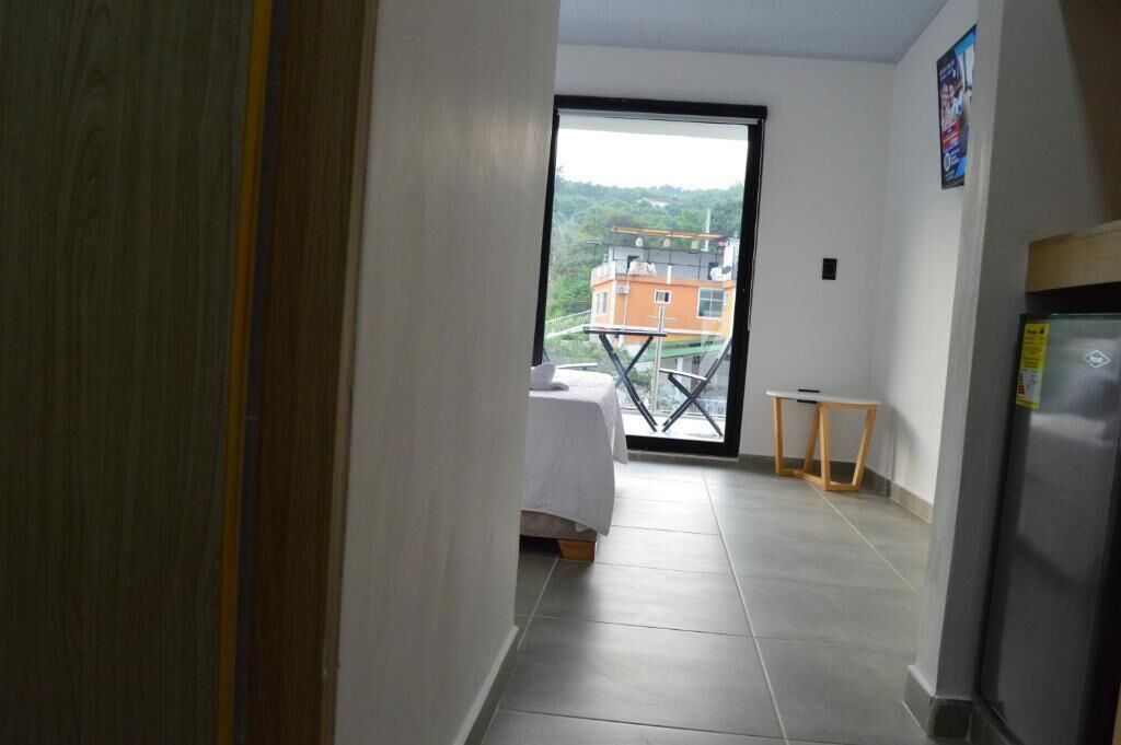 A narrow hallway leading to a balcony with a bed and a small table.