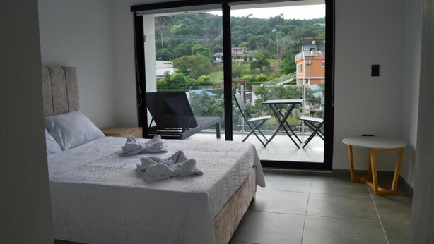 A bedroom with a bed, a small table, and a balcony with a chair and a table. - hotel guacamayas resort vacation (La Mesa)