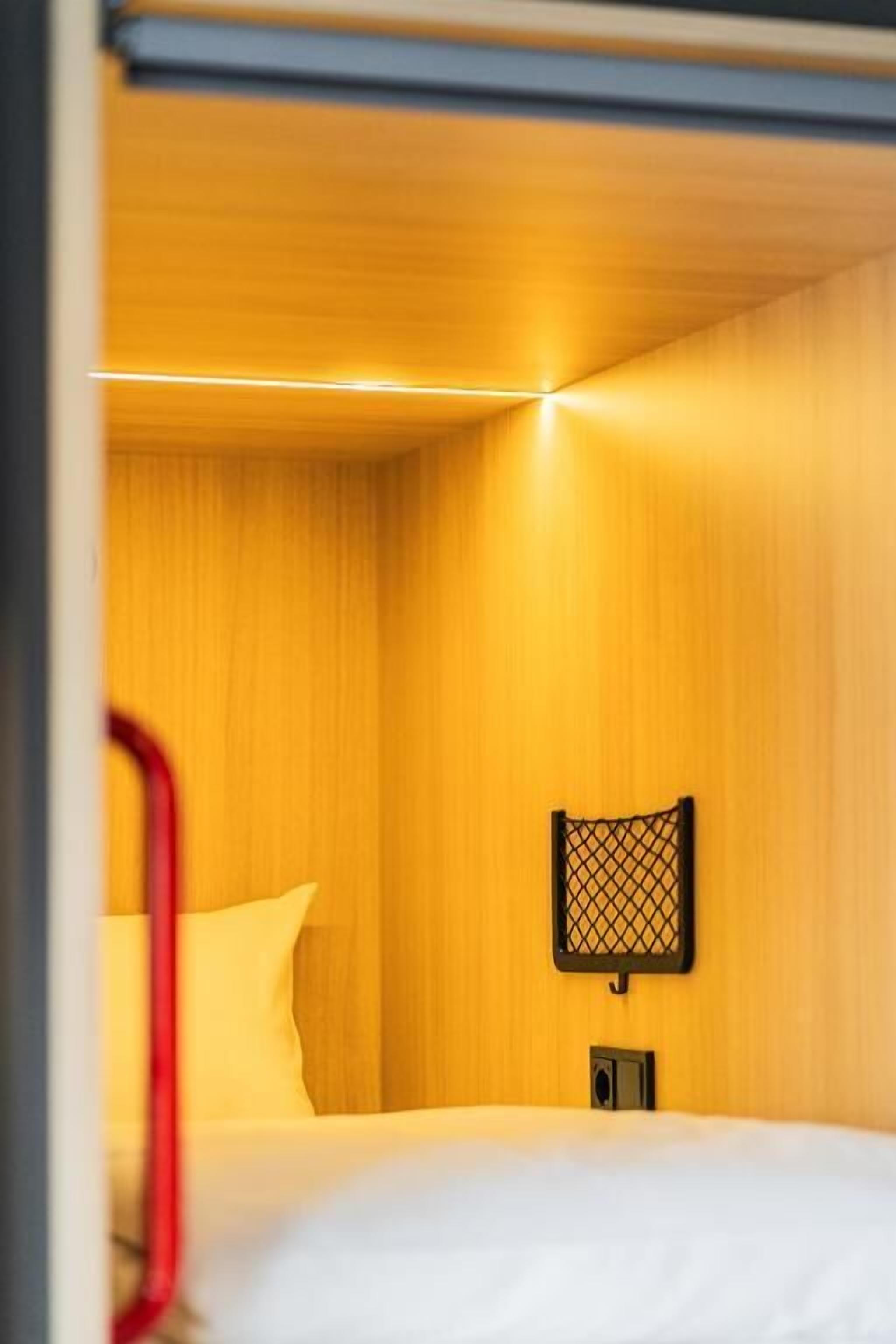 A hotel room with a bed, a nightstand, and a wall-mounted lamp.