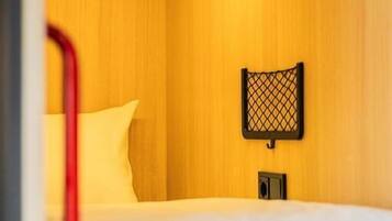 A hotel room with a bed, a nightstand, and a wall-mounted lamp.
