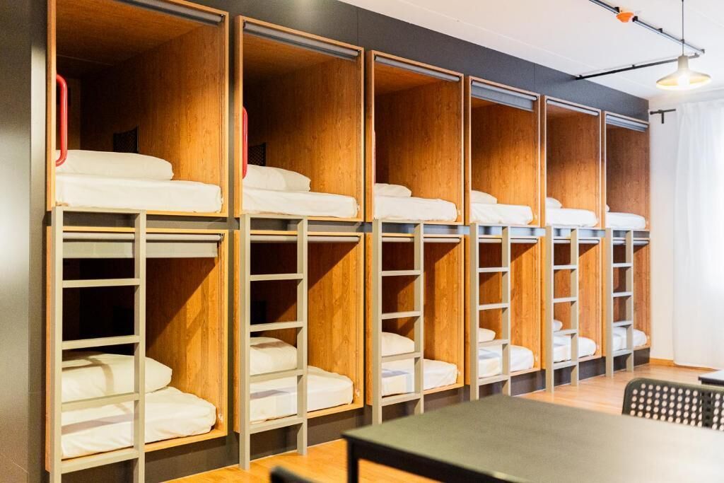 A room with bunk beds, wooden paneling, and a table.