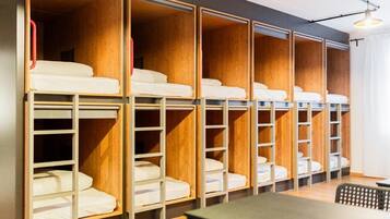 A room with bunk beds, wooden paneling, and a table.