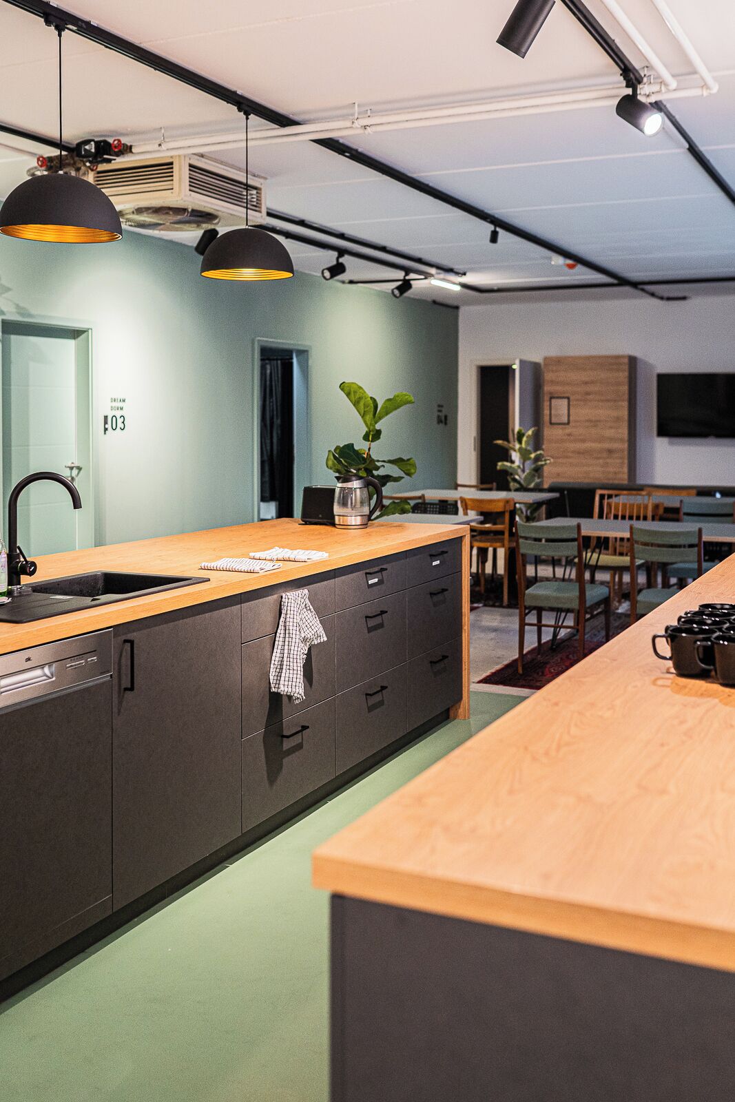 A modern kitchen with a central island, pendant lighting, and a dining area with chairs and a table.