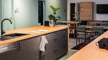 A modern kitchen with a central island, pendant lighting, and a dining area with chairs and a table.