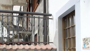 Eine Steinsäule mit Kamin, einem Eisengitter und einer Tür mit Fenster.