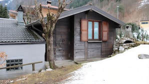 Eine rustikale Holzhütte mit Steinkamin, Holzläden und einer kleinen Veranda.