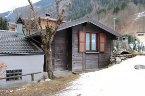 Eine rustikale Holzhütte mit Steinkamin, Holzläden und einer kleinen Veranda.
