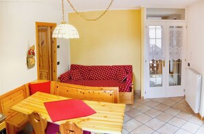 Ein gemütliches Zimmer mit einem Holzespeisetisch, einem roten Sofa und einer Pendelleuchte.