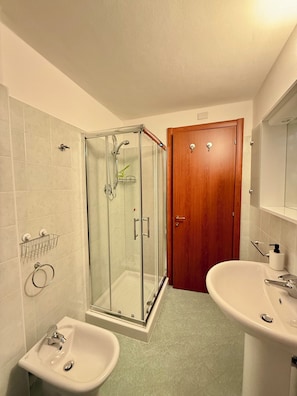 Un bagno con box doccia in vetro, due lavabi e una porta in legno.