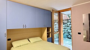 A bedroom with a bed, a wardrobe, and a bathroom. - Casa Via Vai - Casa in Scalve (Valle Richetti)