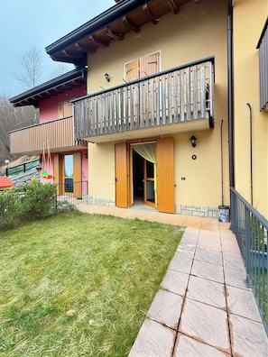 Un edificio a due piani con un balcone, una porta in legno e un sentiero in pietra che conduce all'ingresso.